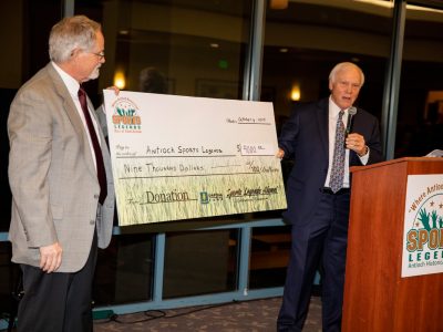 Alumni President, Steve Parks presents a whopping $9,000.00 Alumni check to Antioch Sports Legends Tom Lamothe accepts.